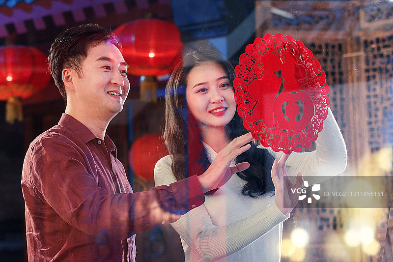 青年夫妇贴窗花图片素材