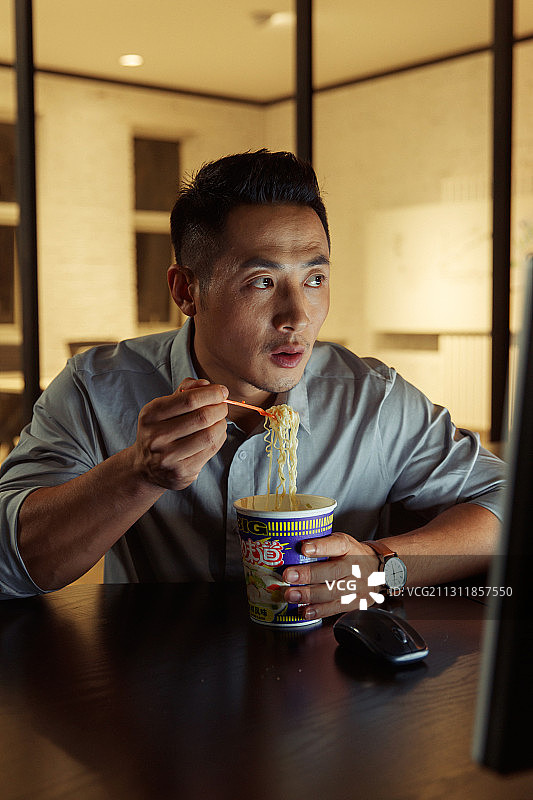 在办公室加班吃方便面的青年男人图片素材