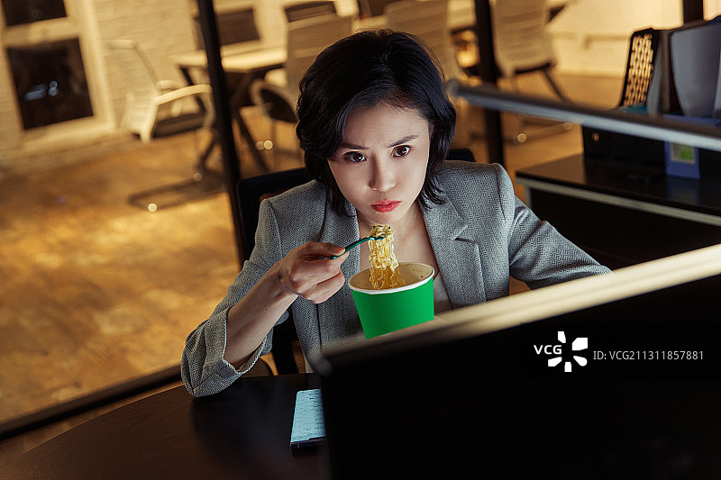 在办公室加班吃方便面的青年女人图片素材