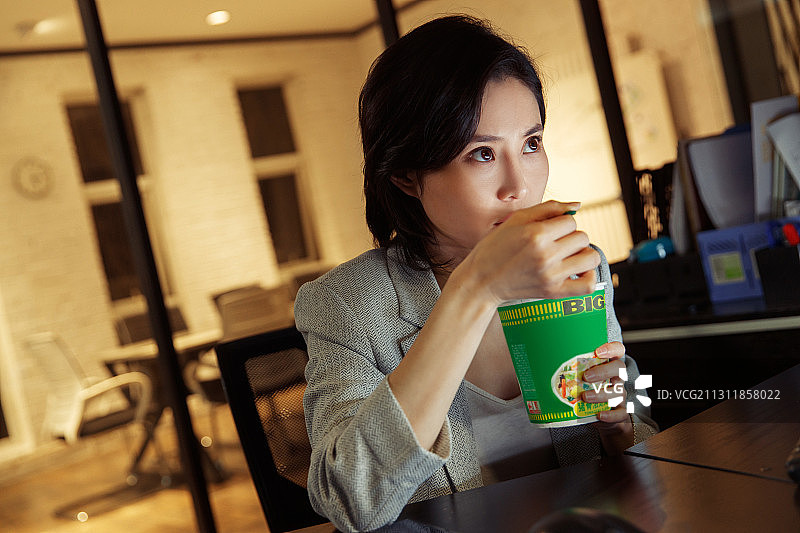 在办公室加班吃方便面的青年女人图片素材