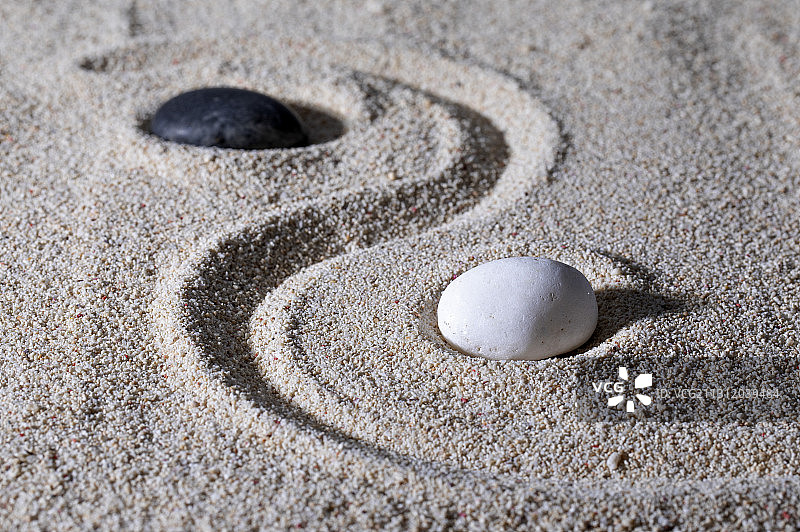 ,沙子上面放着黑白两块石头拼成的太极图案图片素材