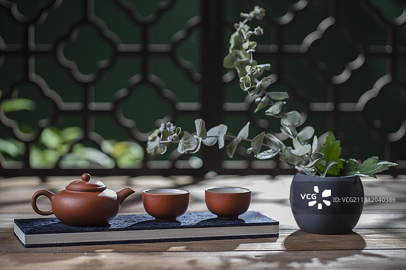 月光下窗花旁桌上的中国茶壶和茶杯富有禅意图片素材