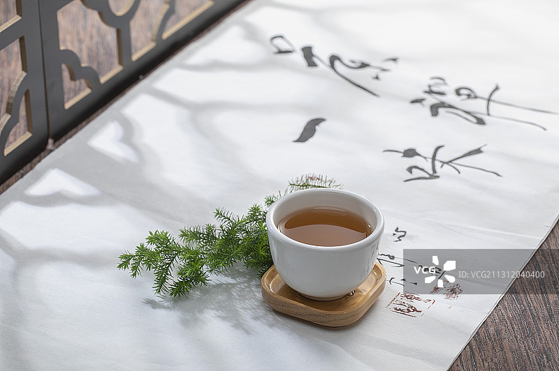 窗花前的茶杯在一幅书法画上富有禅意图片素材