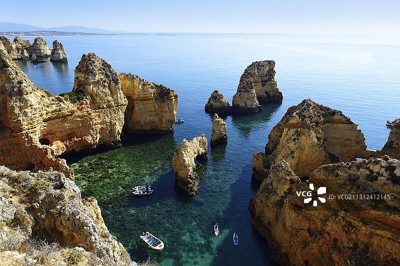 葡萄牙拉各斯蓬塔达皮耶达德湾的游览船和桨板冲浪者图片素材