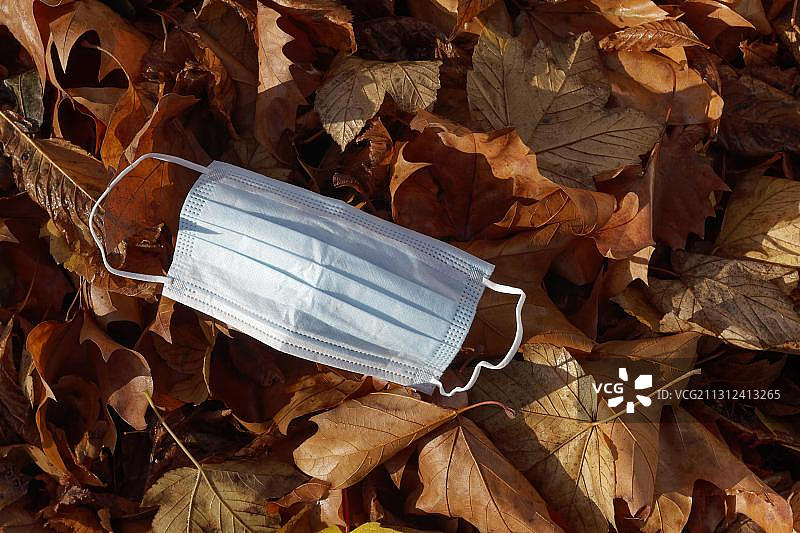 疫情期间丢弃在落叶上的口罩图片素材