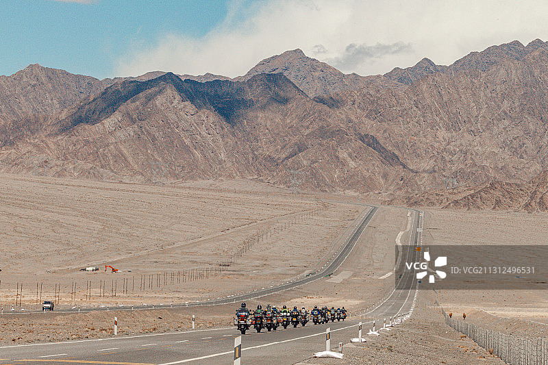 中国青海，绵延的山脉，一望无际的戈壁，摩托车车队正在穿越荒漠图片素材
