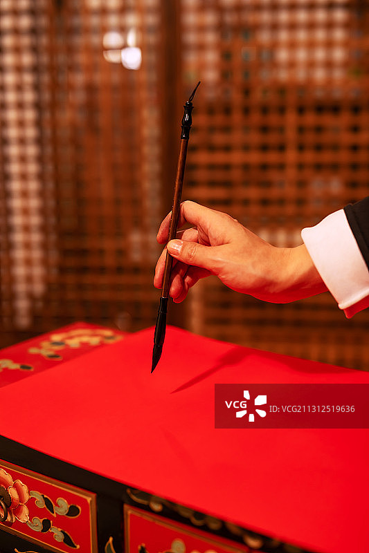 一个东方男子手拿毛笔写春联图片素材