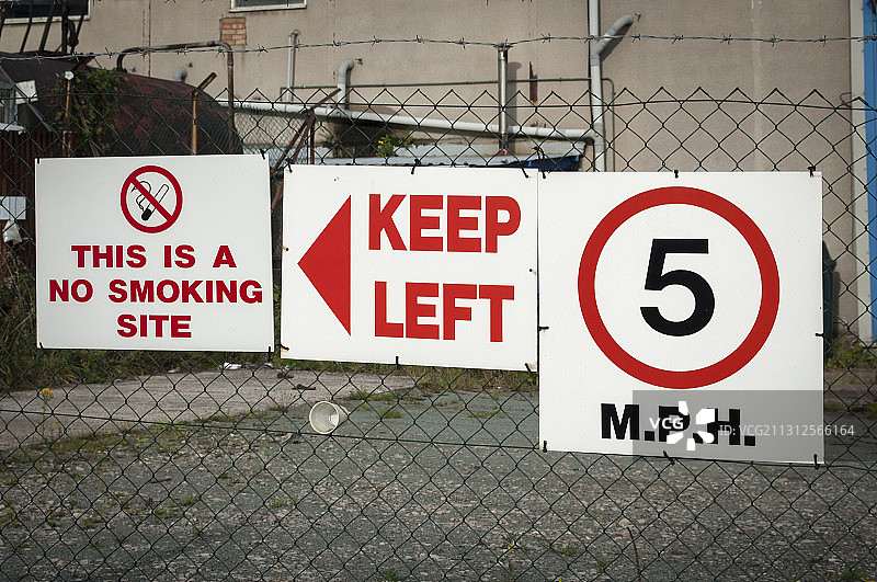 工业厂区带刺铁丝网上的警告标志图片素材