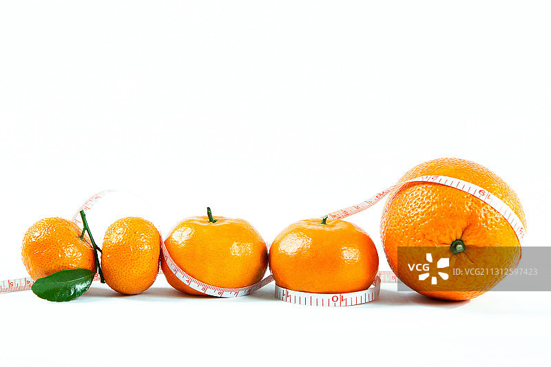 皮尺卷起来的四个橘子和一个橙子图片素材