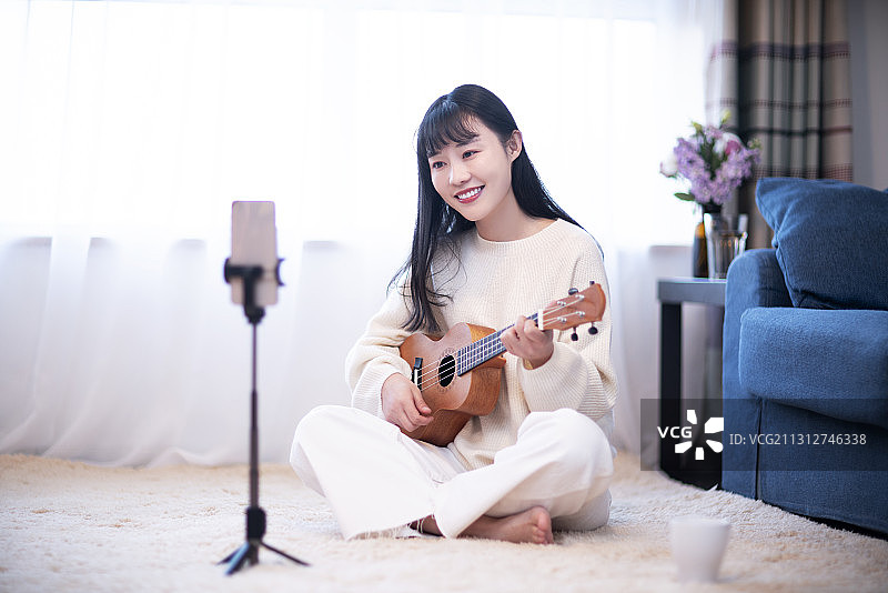 年轻女士在家网络直播弹奏吉他图片素材