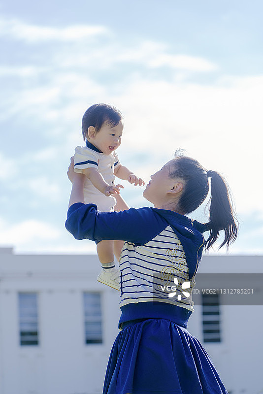 校园教学楼前母亲双手托起婴儿图片素材