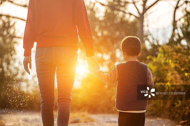 妈妈牵着宝宝走在温暖的朝阳中图片素材