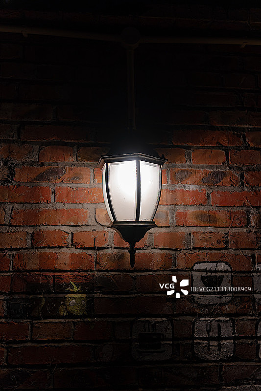 黑暗中红砖墙上一盏金属路灯图片素材