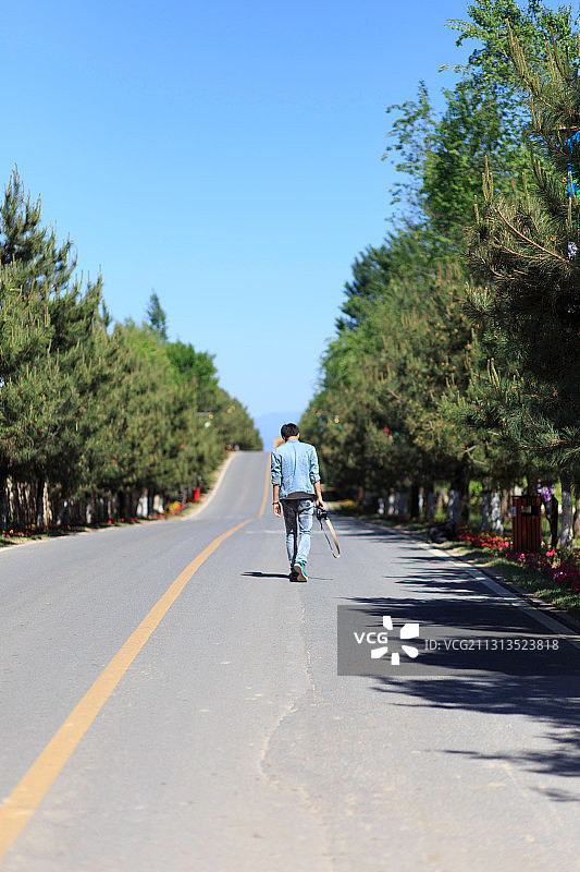 在一个晴朗的天气里在公路上独自行走的人图片素材