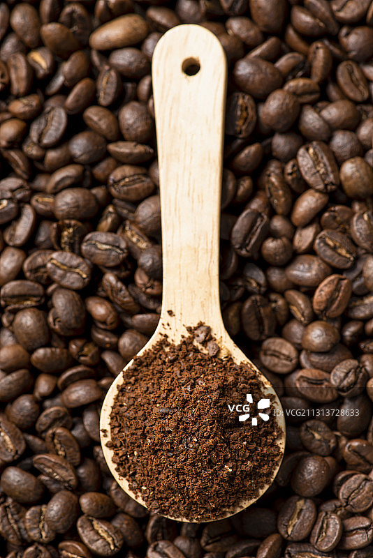 堆叠的烘焙咖啡豆上的咖啡粉木勺图片素材
