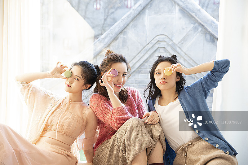 三个闺蜜居家聚会吃马卡龙闲谈聊天图片素材