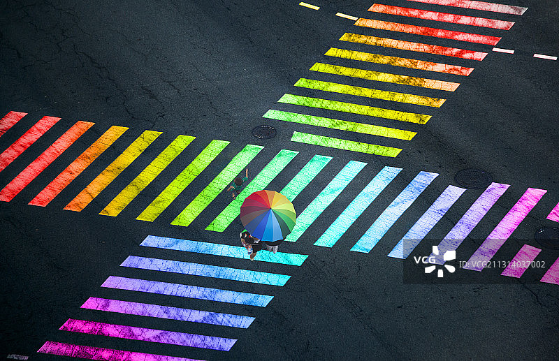 打着彩虹伞走在彩虹斑马线上图片素材