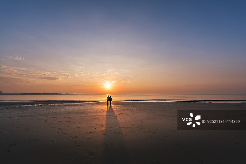 一对在海滩上看日出的老人图片素材