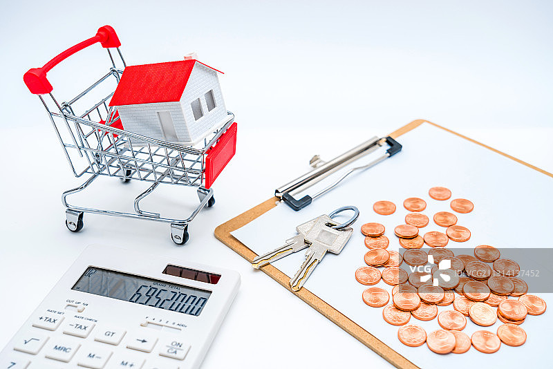 白色背景下的房子模型、计算器、钱币和钥匙——买房子概念图片图片素材