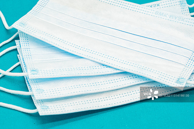 蓝色背景下整齐排列的医用口罩图片素材