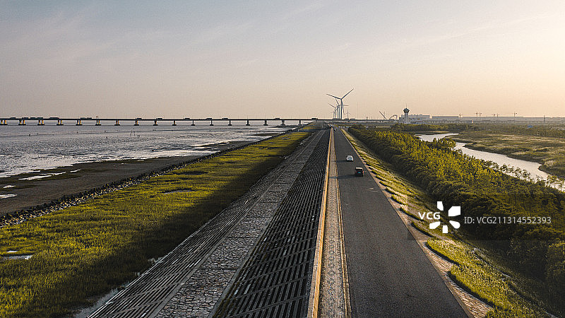 落日下的海堤公路上行驶着车辆图片素材