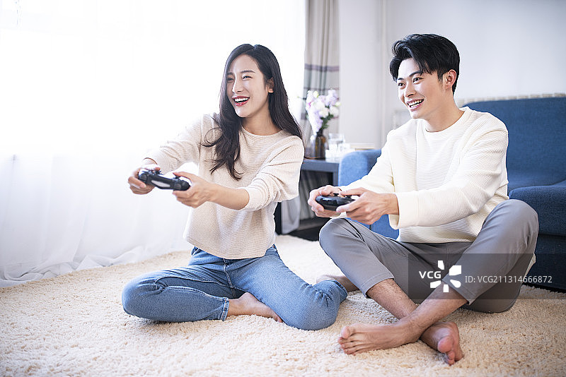 年轻情侣在家使用智能手机玩游戏图片素材