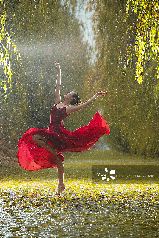 穿红色裙子的青年女人在户外跳芭蕾舞图片素材