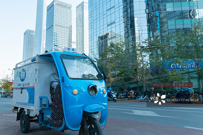 工作途中驾驶三轮车的快递员图片素材
