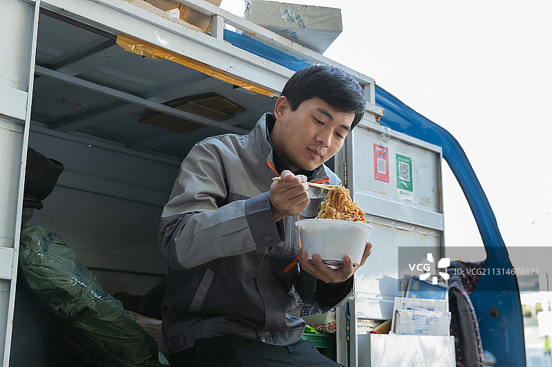 快递员坐在快递车上吃面图片素材