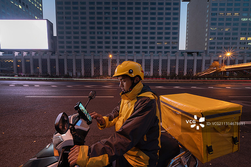 路边查看手机订单的外卖员图片素材