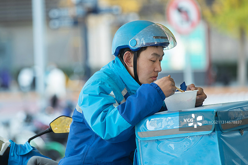 外卖员在街道旁吃饭休息图片素材