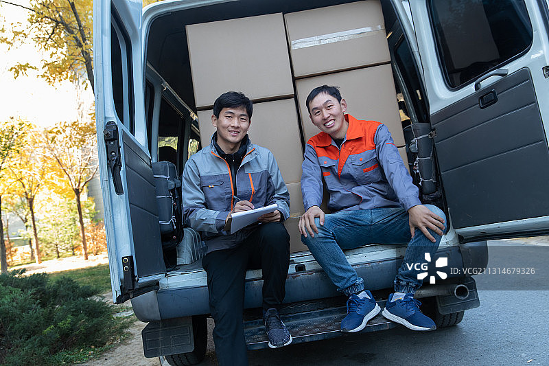 坐在货车上面清点货物的工作人员图片素材