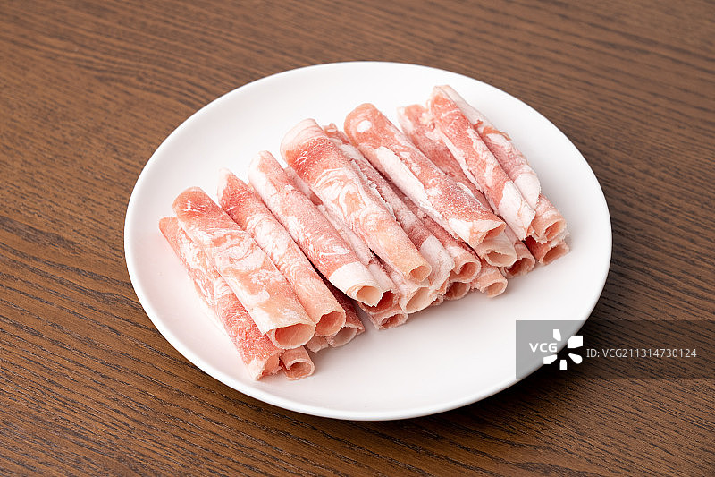 褐色木板上盘子里的鲜美肥羊肉卷图片素材