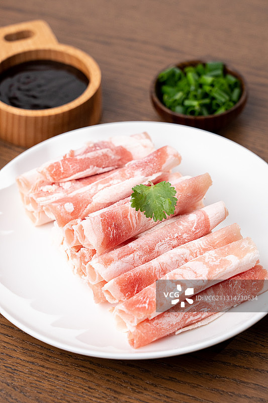 木板上生鲜食材火锅主菜羊肉卷和碟子上的配菜配料图片素材