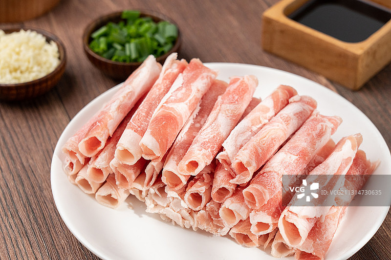 木板上生鲜食材火锅主菜羊肉卷和碟子上的配菜配料图片素材