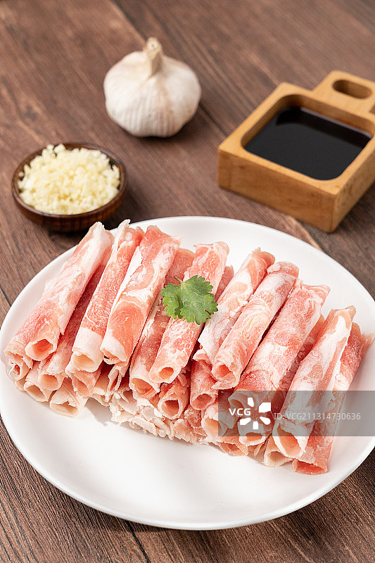 木板上生鲜食材火锅主菜羊肉卷和碟子上的配菜配料图片素材