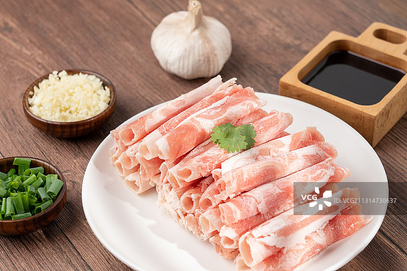 木板上生鲜食材火锅主菜羊肉卷和碟子上的配菜配料图片素材