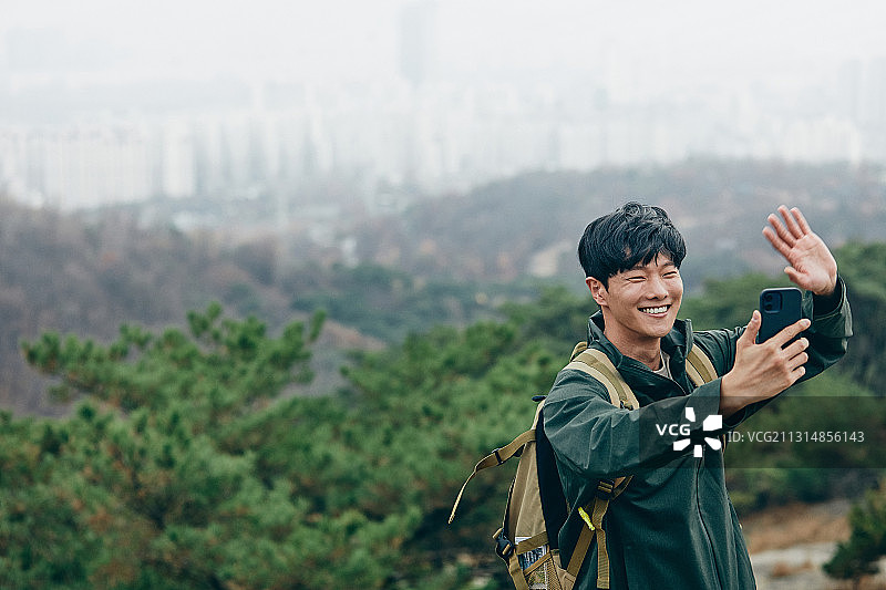 男人在森林独自登山，智能手机视频通话招手图片素材