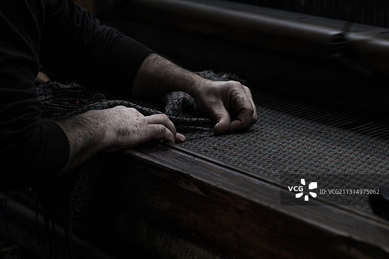 在桌子上处理纺织品的男子（中部视角），葡萄牙曼泰加斯图片素材