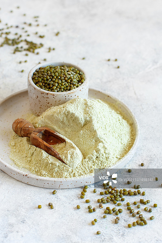 盘子里的绿豆粉和谷物与木制勺子图片素材