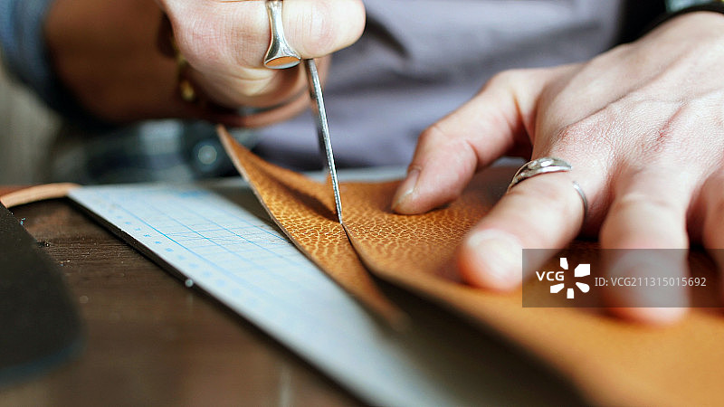 男人切割皮革制作钱包的特写图片素材