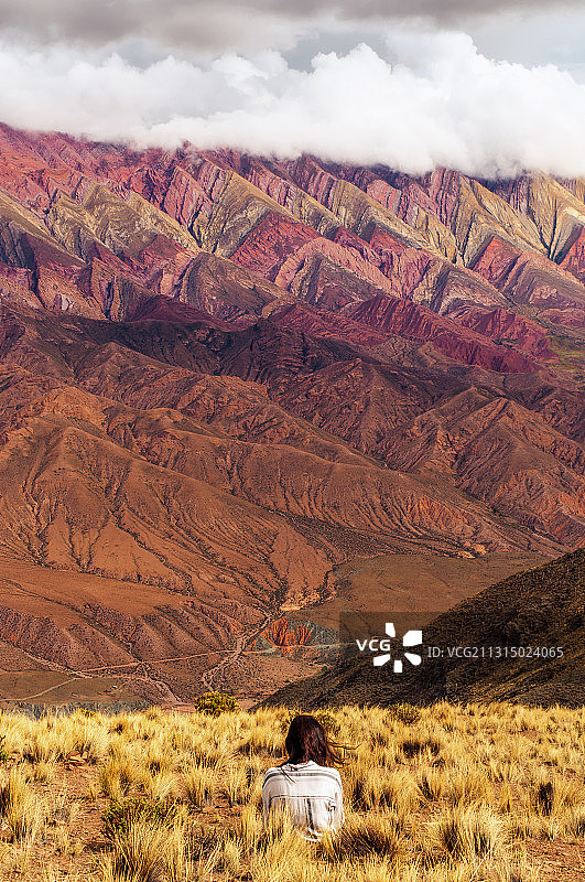 年轻女子坐在阿根廷胡胡伊彩色山前的背影图片素材