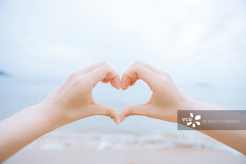 在中国，女人手对着大海比心的裁剪图图片素材