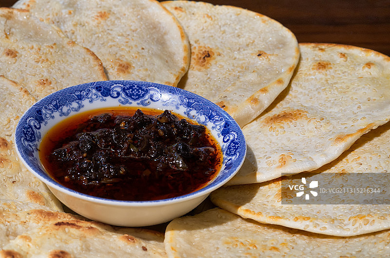 围绕一碟蘸酱平铺的成一圈的芝麻烧饼图片素材