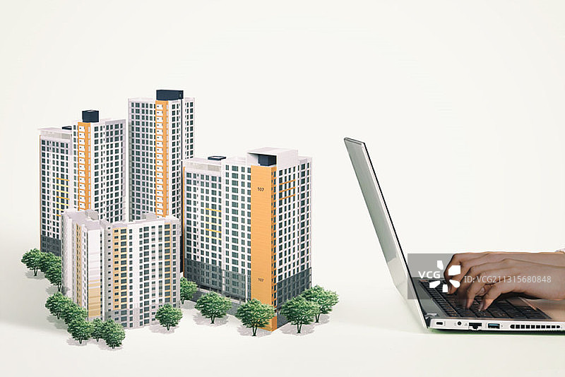 在笔记本电脑和公寓模型上搜索房地产价格图片素材