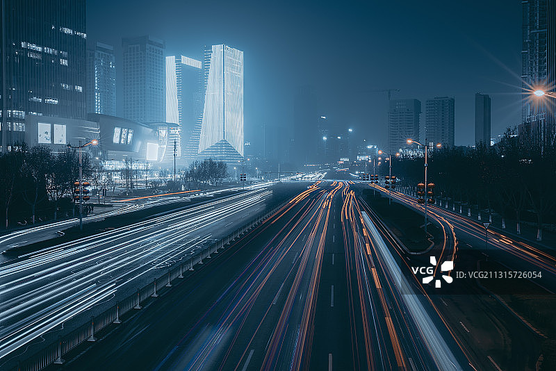 夜晚行驶中车辆的灯光在经十路上形成了车轨图片素材