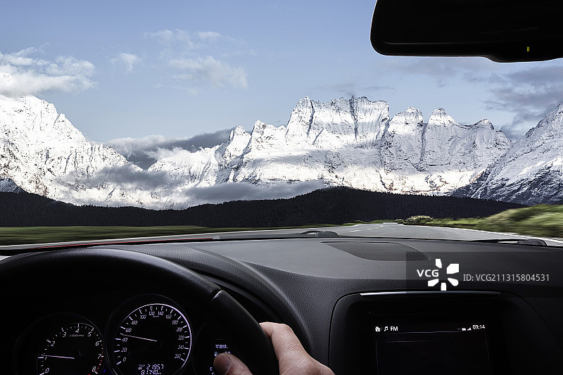 驾驶汽车在通往雪山的路上图片素材