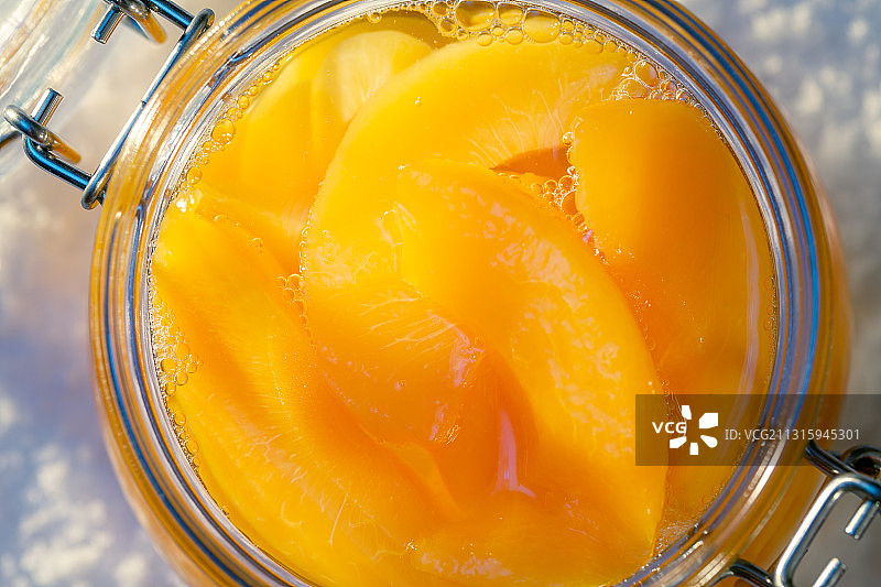 晴天雪地上玻璃储物罐里的黄桃罐头图片素材