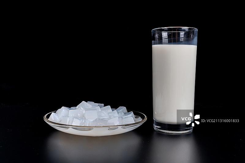 黑色背景下切块椰肉和玻璃杯里的椰汁图片素材