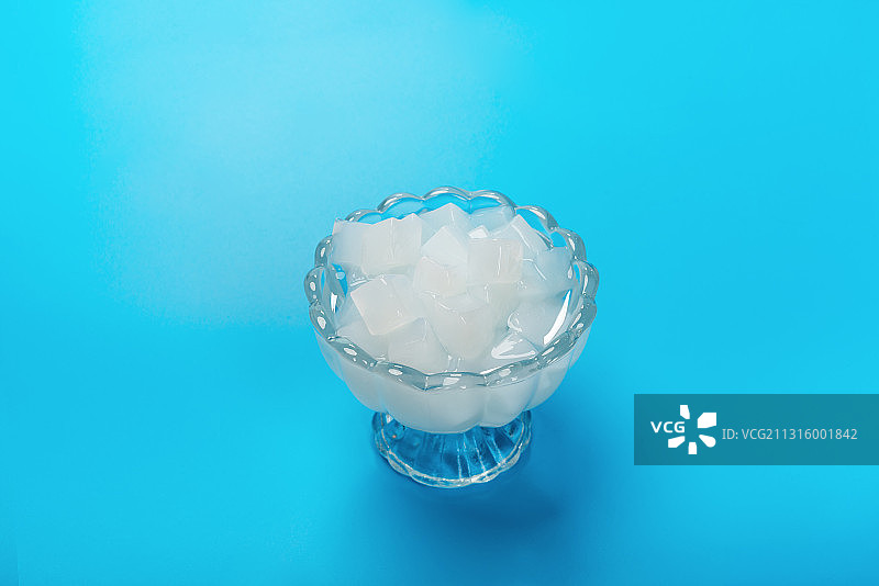 蓝色背景下高脚玻璃杯的椰肉图片素材